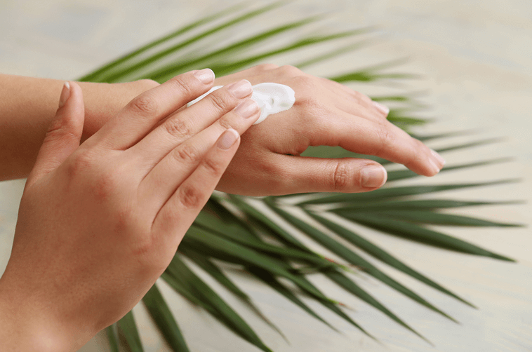 Person cremt sich ihre trockenen Hände ein.