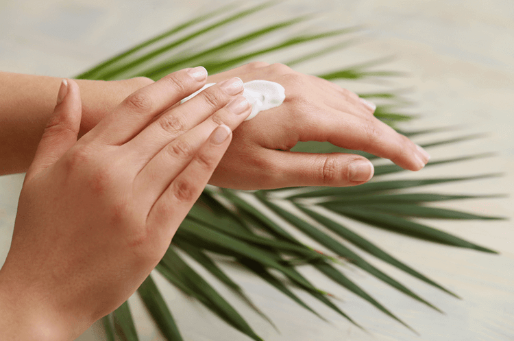 Person cremt sich ihre trockenen Hände ein.